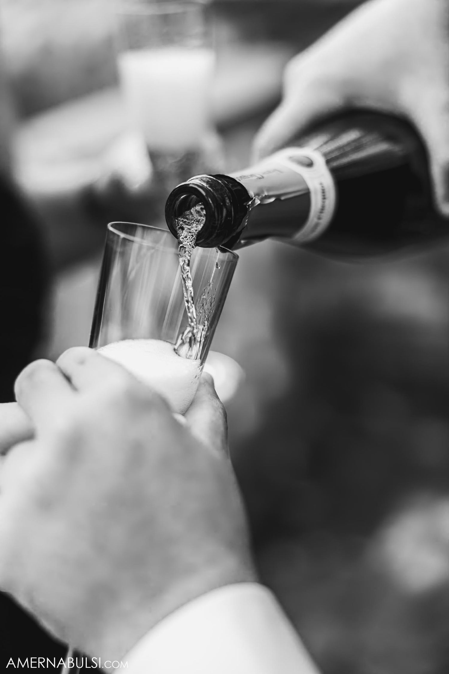 Black and white photo of champagne being poured into a glass during a celebration.