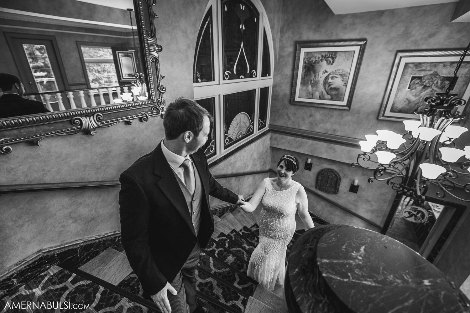 Dramatic black and white photo on ornate spiral staircase with arched windows.