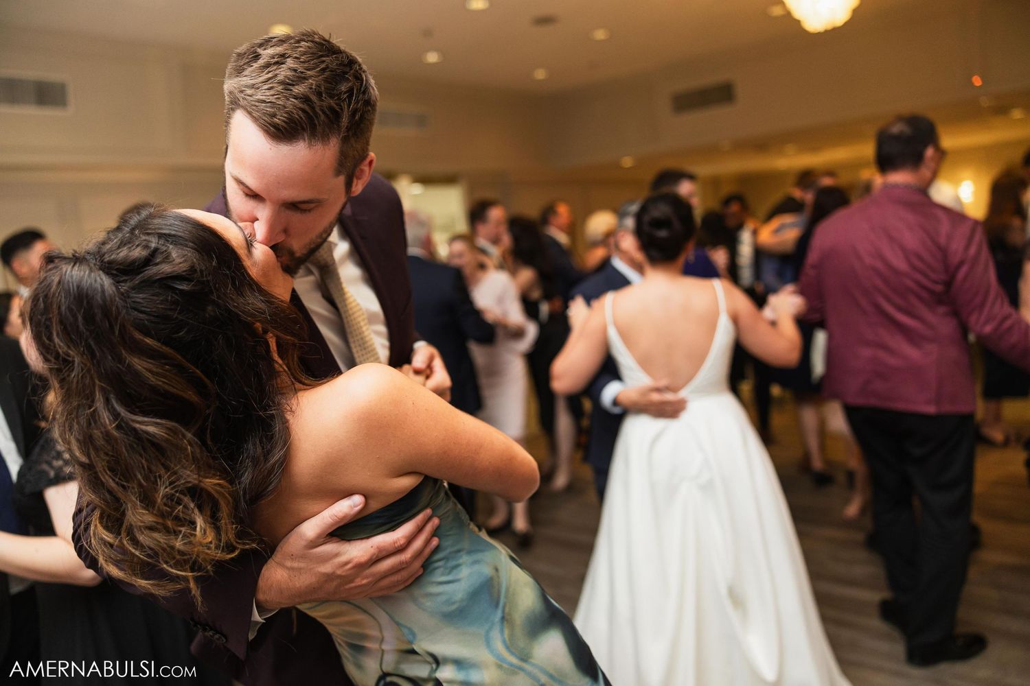 Couples dancing intimately at an elegant wedding reception with guests in background.