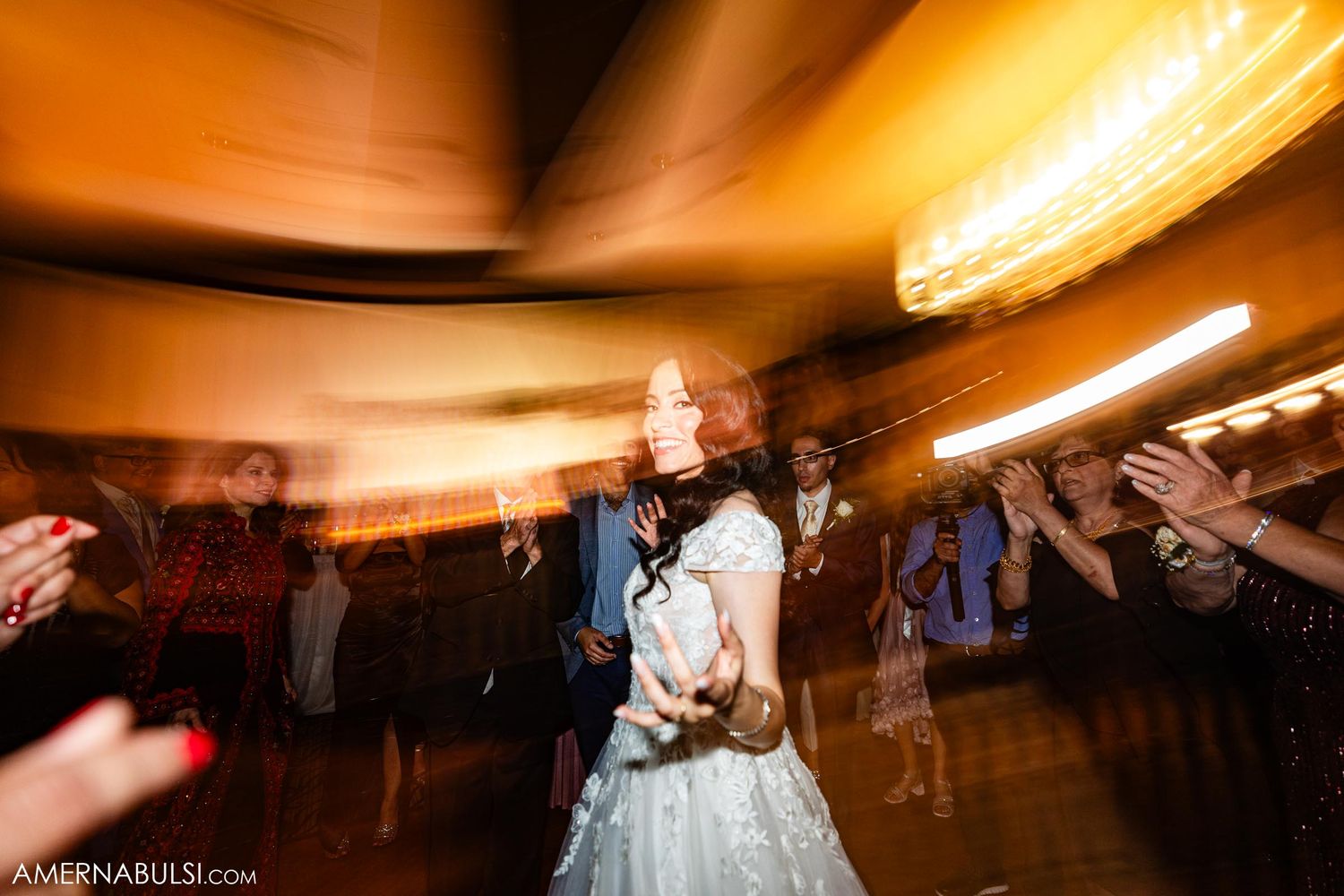 Motion-blurred photo of a bride dancing under dramatic orange lighting at a wedding reception.
