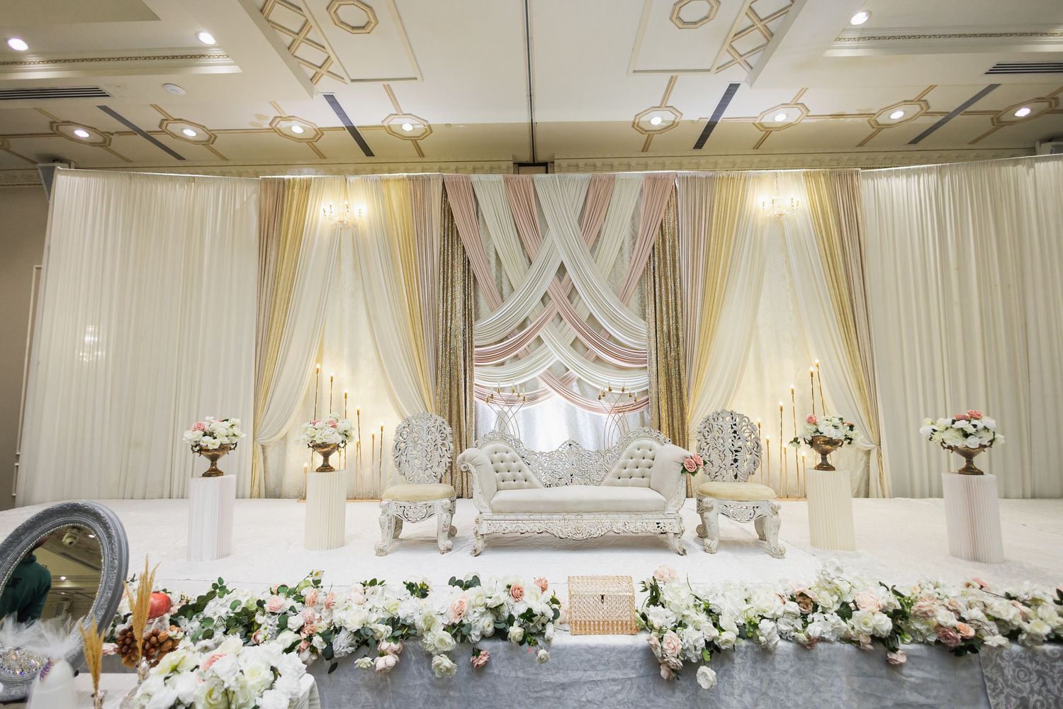 Grand ballroom with crystal chandeliers and ornate ceiling details decorated in white and gold.