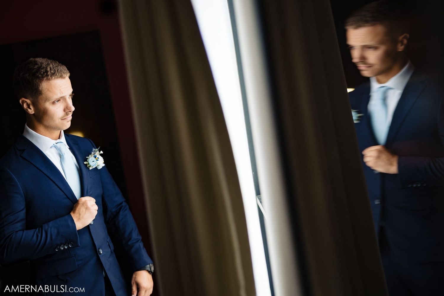 Groomsmen in dark suits prepare in dramatic lighting before the ceremony.