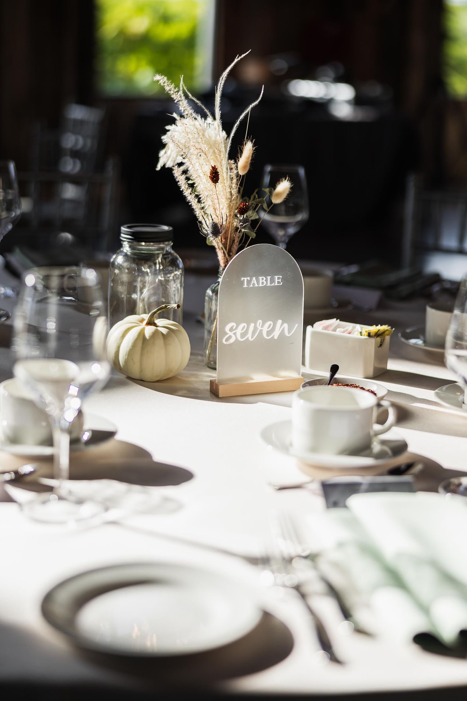 Elegant table setting with white pumpkin and dried flower centerpiece.