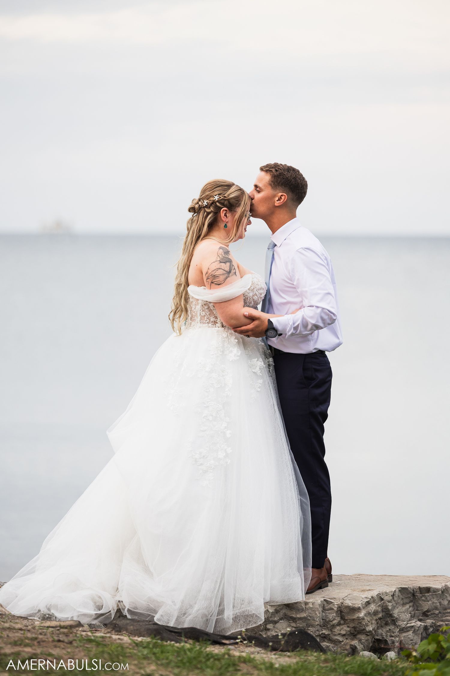 Romantic wedding portraits taken on a rocky beach with a misty ocean backdrop.