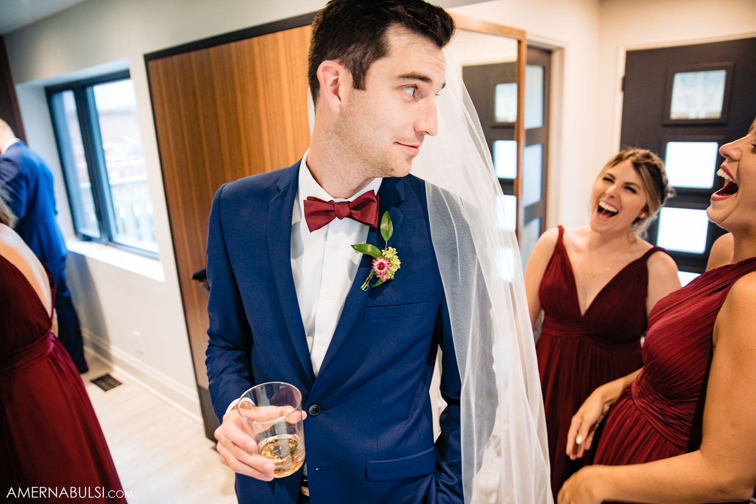 Wedding party members sharing drinks and conversations in an indoor setting.