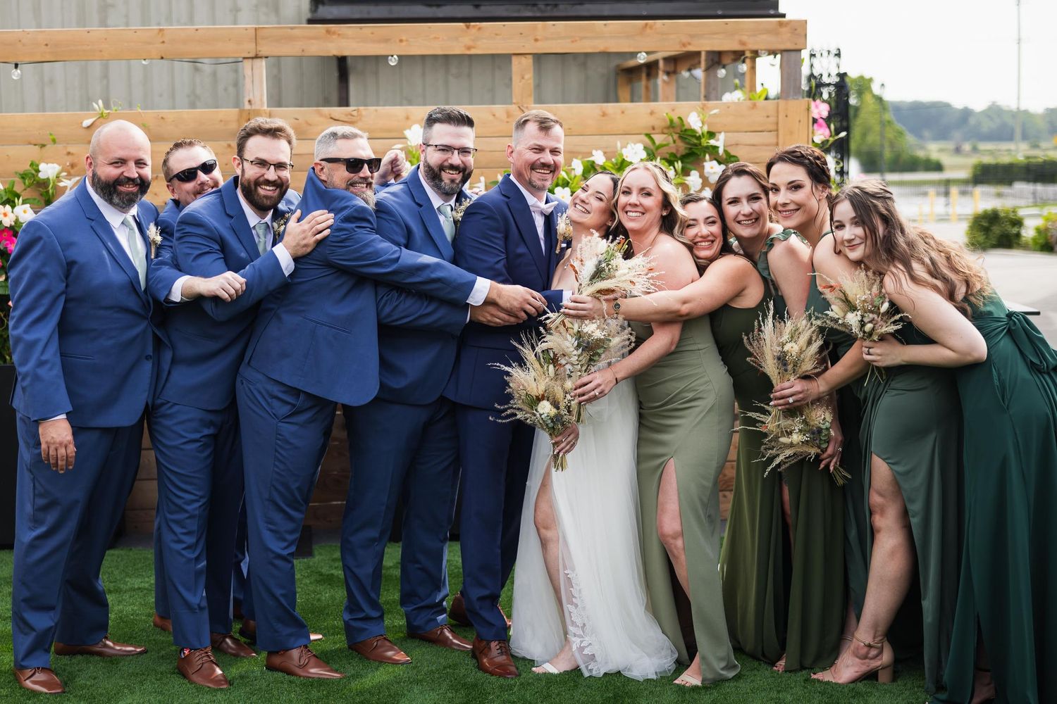 Wedding party in navy and green attire poses playfully outdoors.