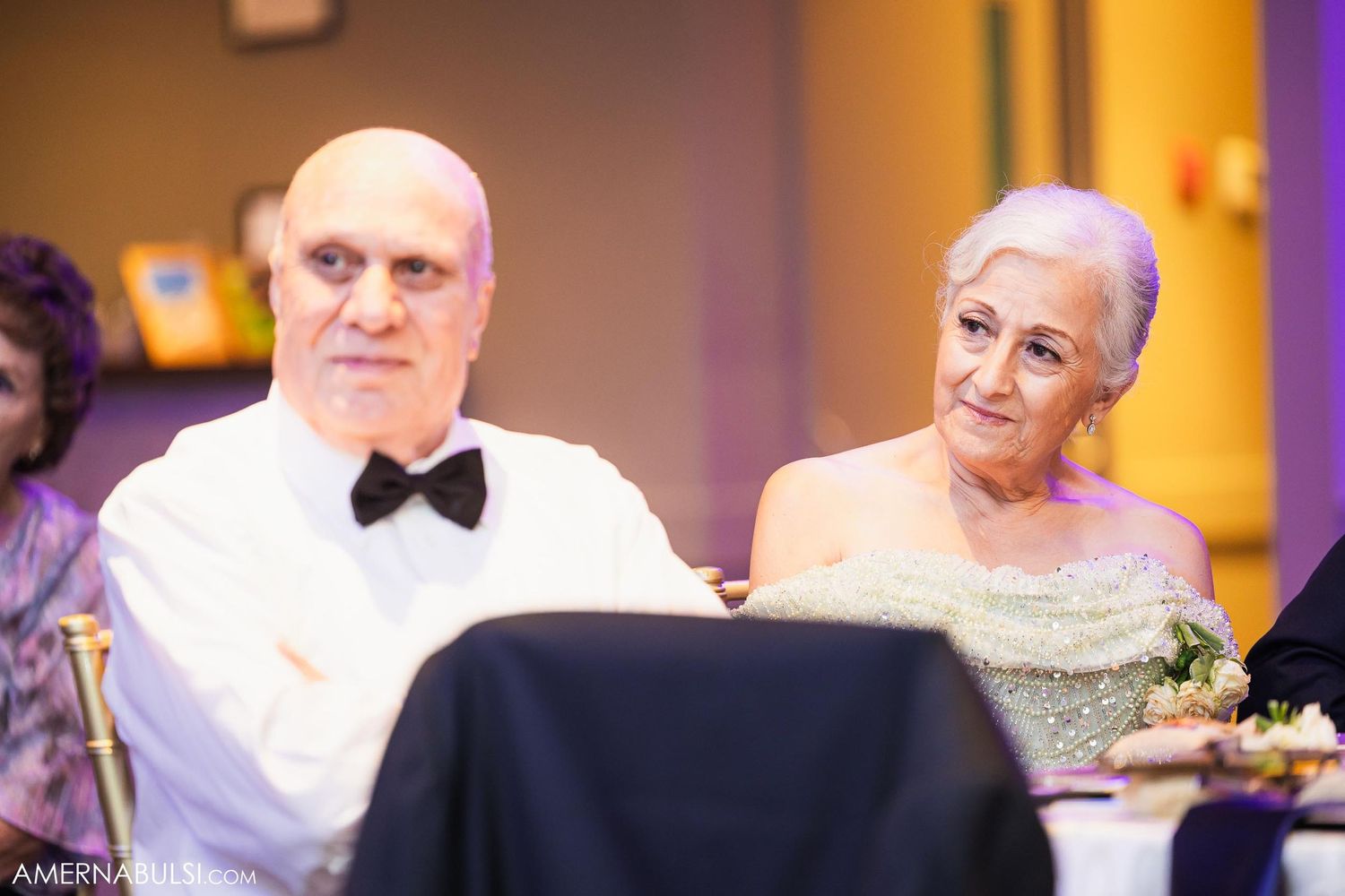 Wedding guests in formal attire seated at reception table.