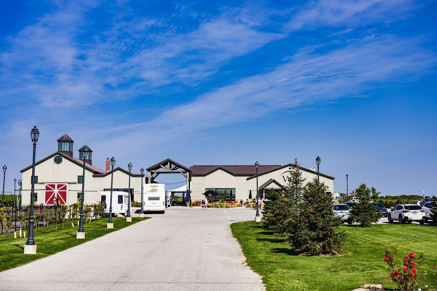 Large winery estate building with white facade and paved driveway under blue sky.