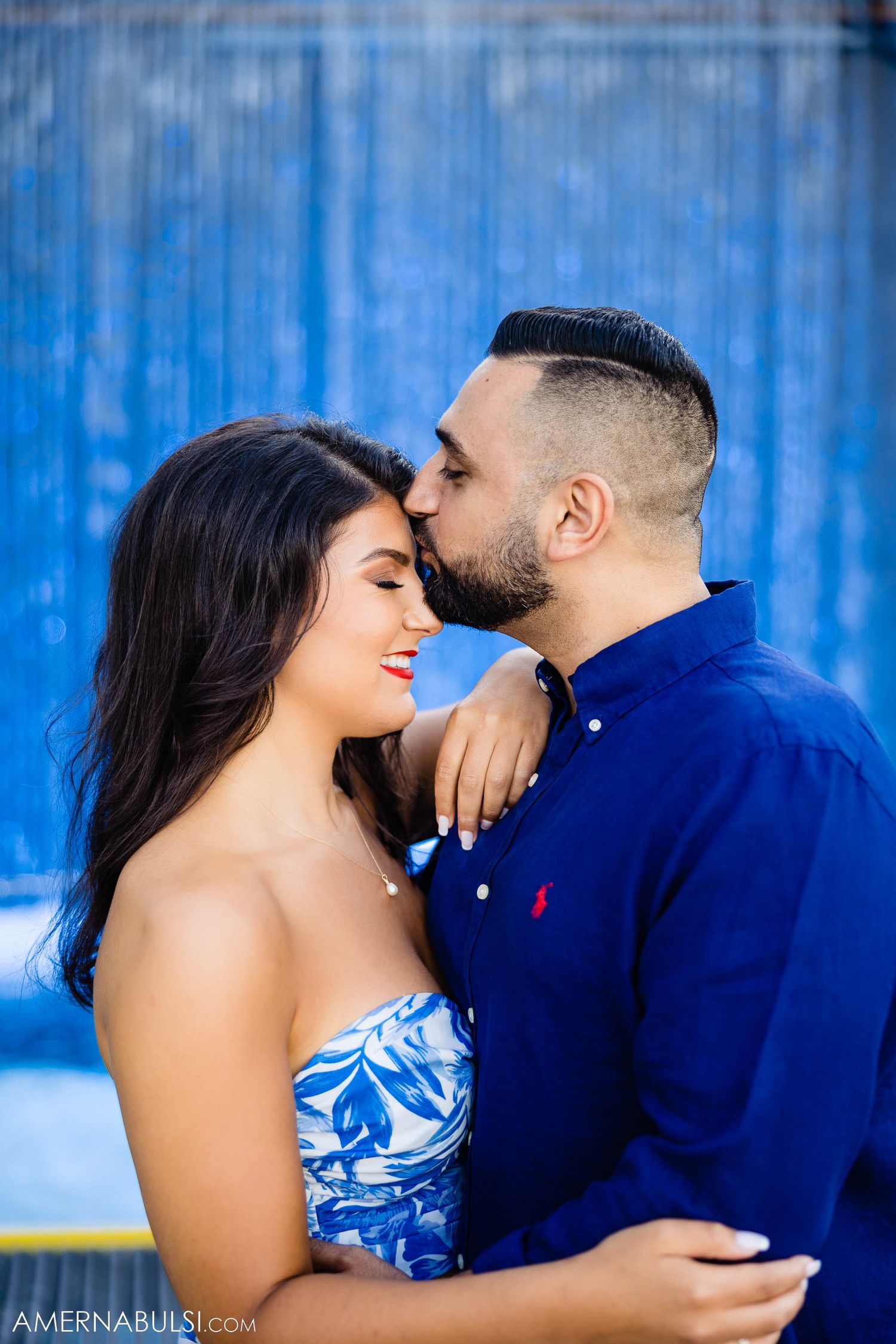 Intimate portrait of couple against vibrant blue background.