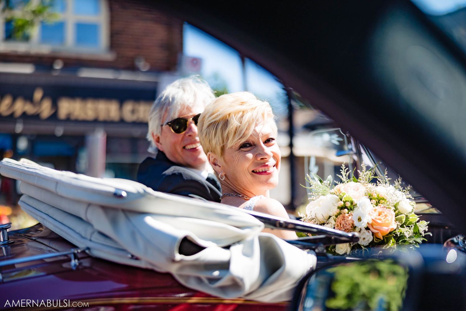 Two people enjoying a scenic drive in a classic convertible car with flowers.