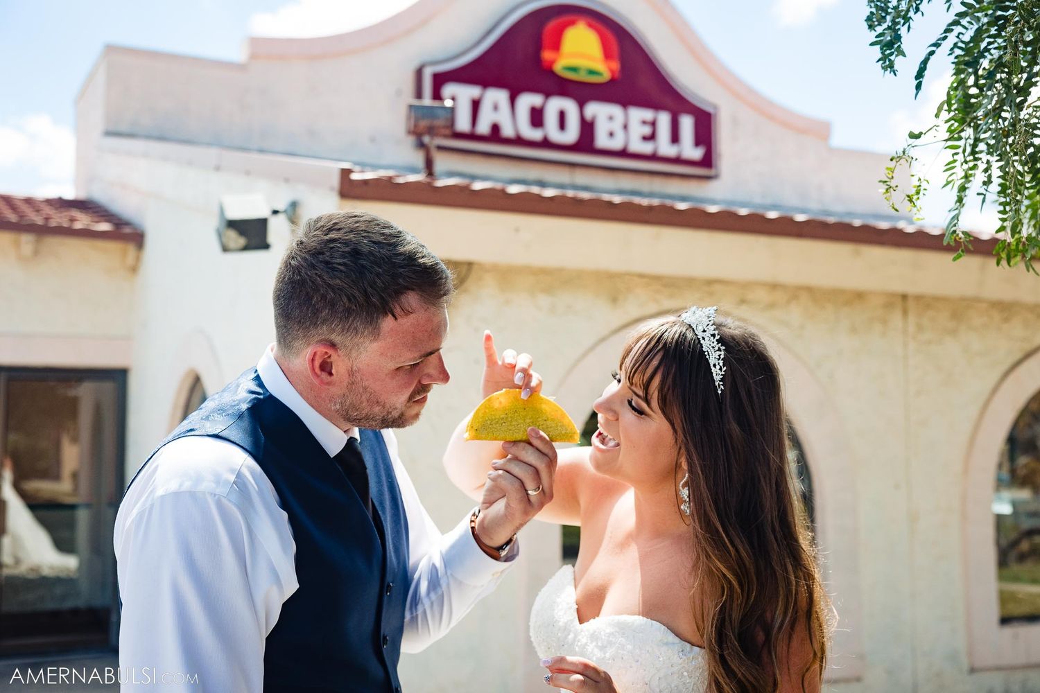 Wedding photo of a couple sharing food outside of a Taco Bell restaurant.