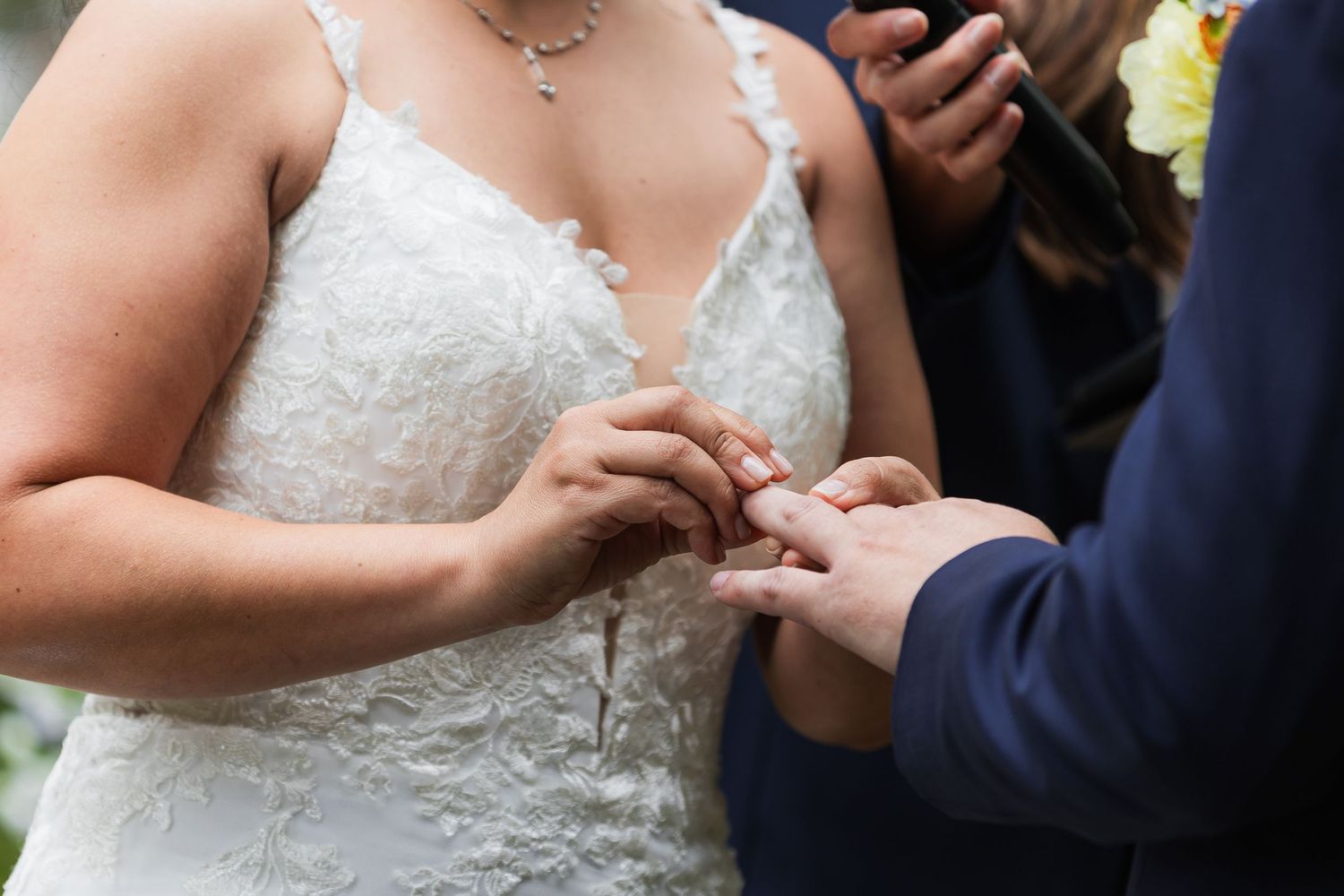 Bride places wedding ring on grooms finger during intimate outdoor wedding ring exchange ceremony.