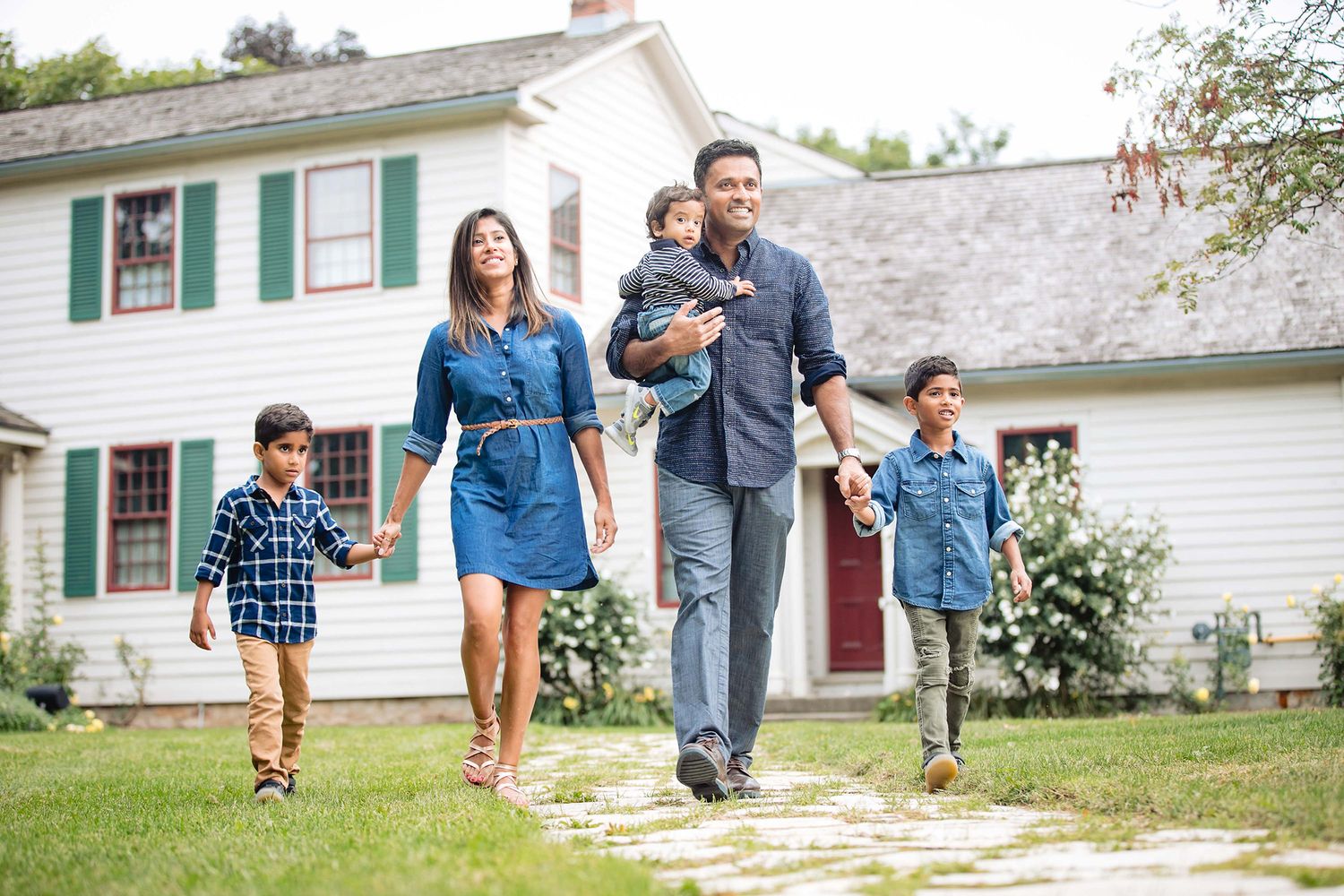 Family walking together on stepping stones in their front yard on a sunny day.