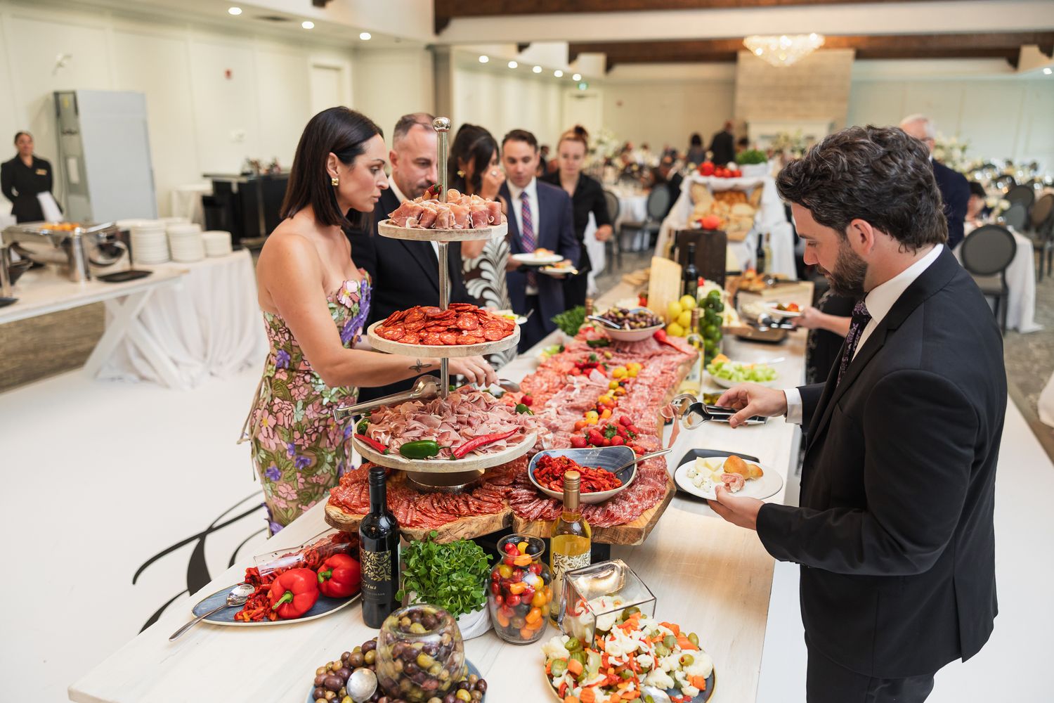 Guests serving themselves at an elaborate wedding cocktail hour seafood and appetizer buffet table.