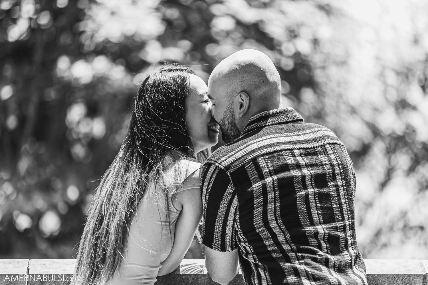 Romantic black and white portrait of a couple sharing an intimate moment on a balcony.