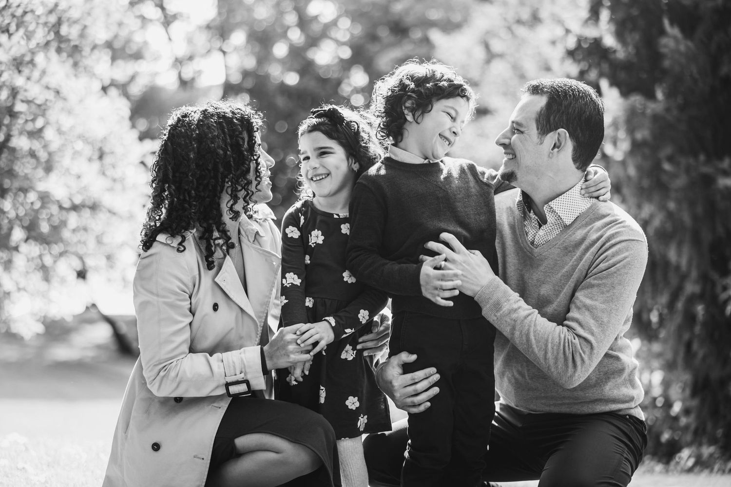 A candid black and white photo of four people laughing together outdoors.
