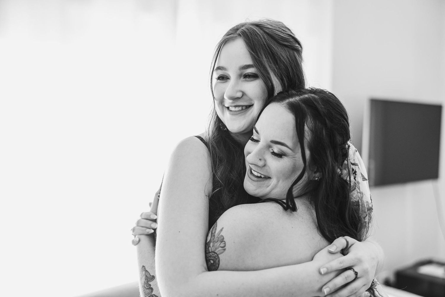 Black and white candid moment of wedding day preparations and embraces.