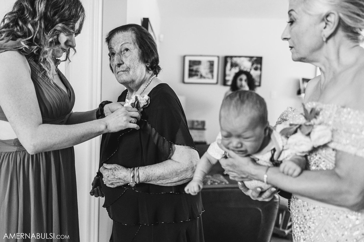 Black and white candid moment of family members helping with wedding preparations.
