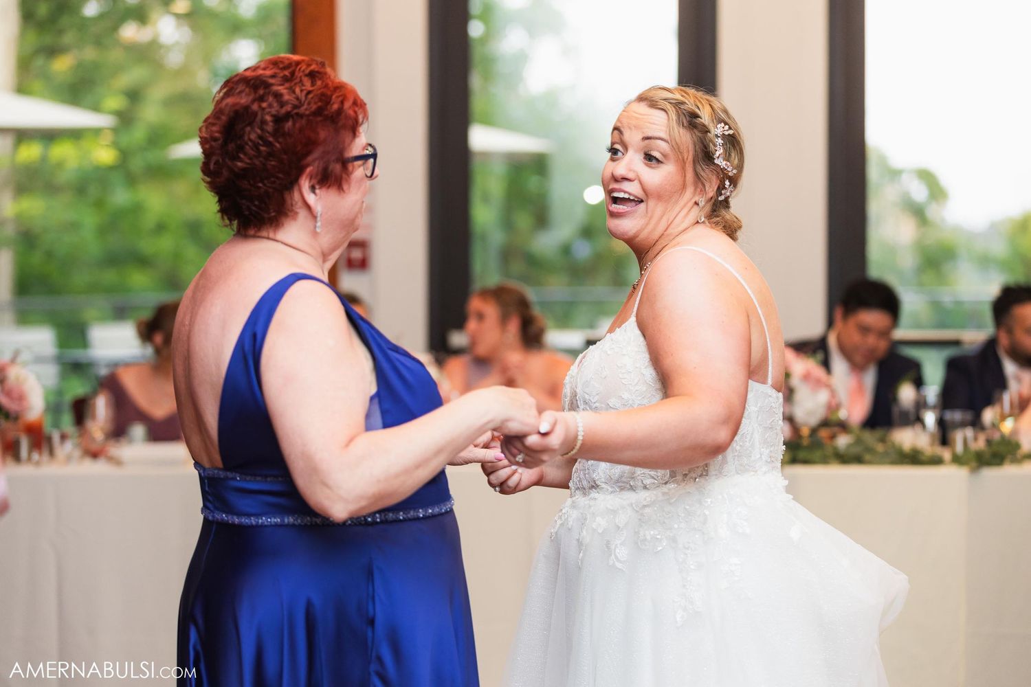 Two wedding guests share an energetic dance moment during the reception celebrations.
