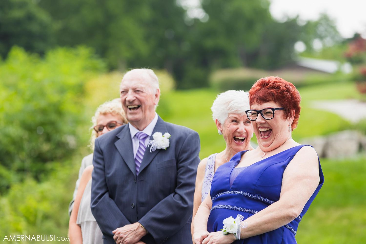 Wedding guests sharing a joyful moment outdoors wearing formal attire.