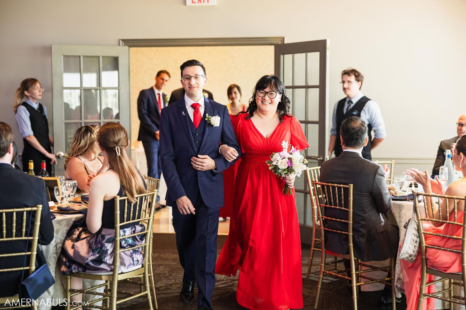 Wedding party members walk through doorway during formal reception entrance.