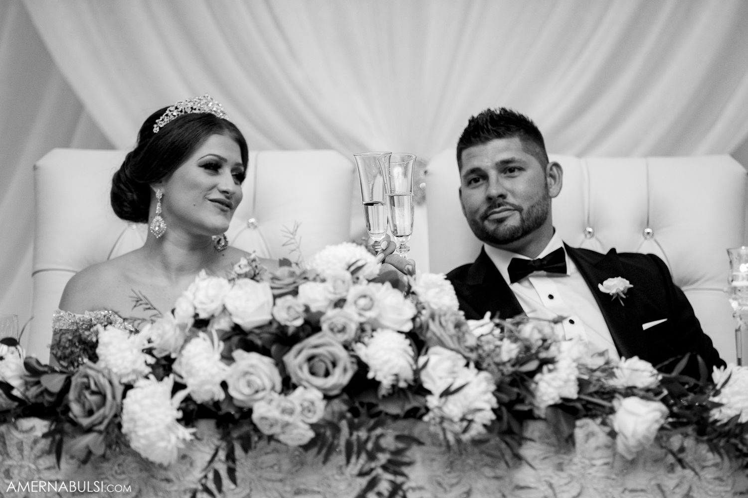 White floral arrangements and roses decorating an elegant wedding reception table.