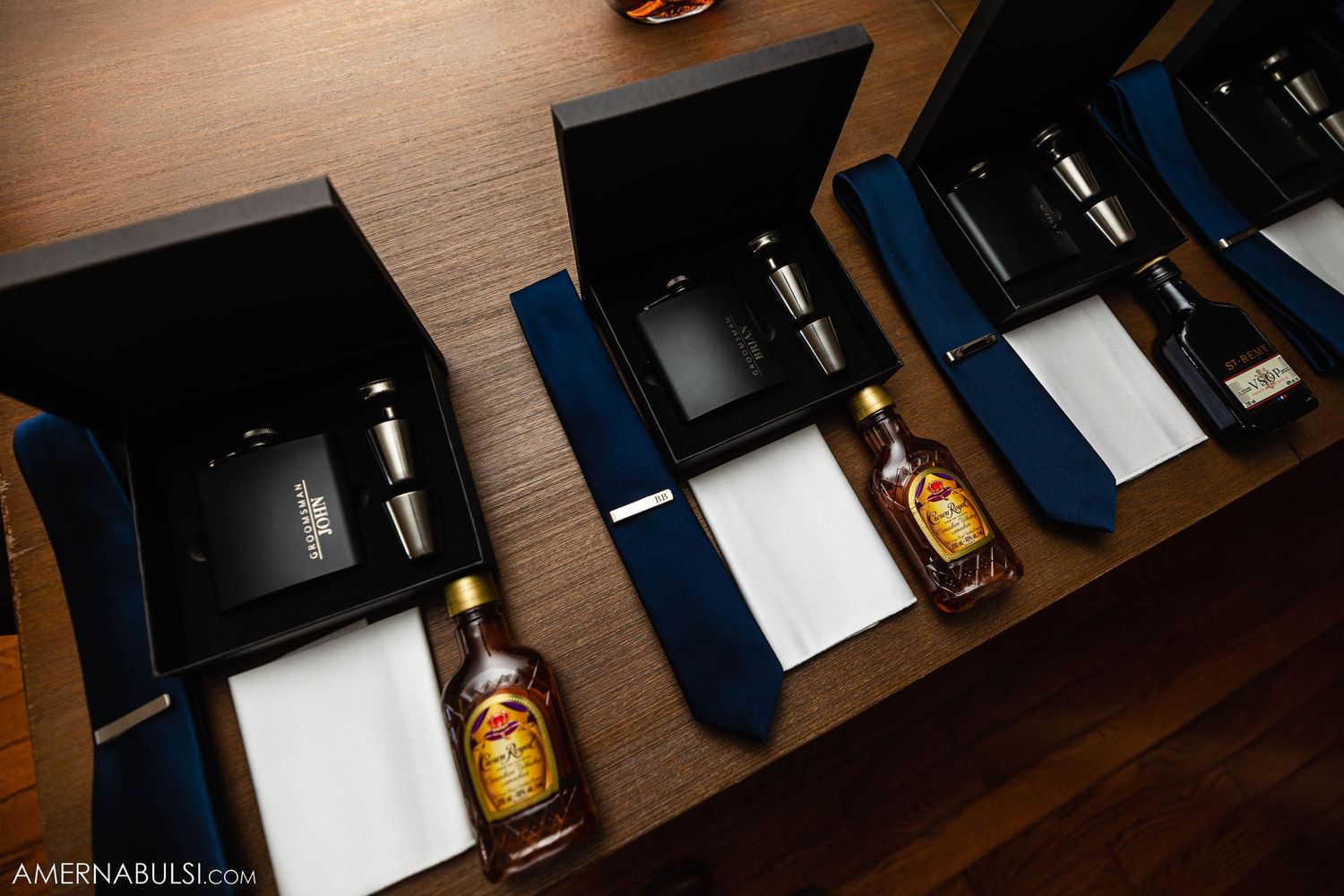 Row of elegant blue gift boxes with bottles displayed on wooden surface.