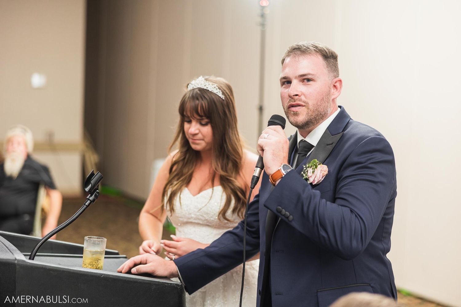 Couple giving wedding speeches at reception podium.