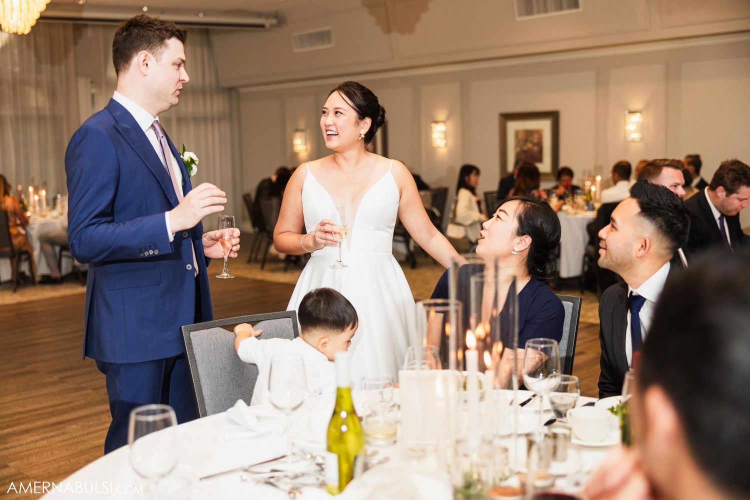 Wedding reception toast moment with guests gathered at decorated dinner tables.