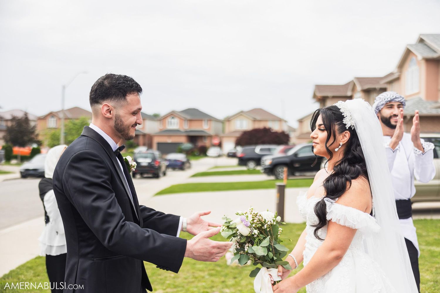 A couple shares a joyous first look moment during their wedding ceremony on a residential street.