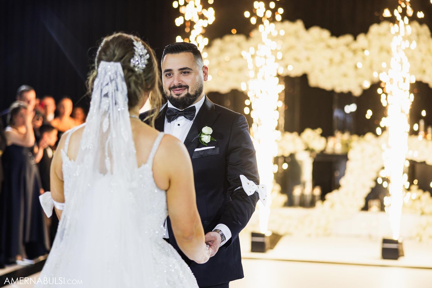 A wedding couple share a joyful moment under romantic string lights during their evening reception celebration.