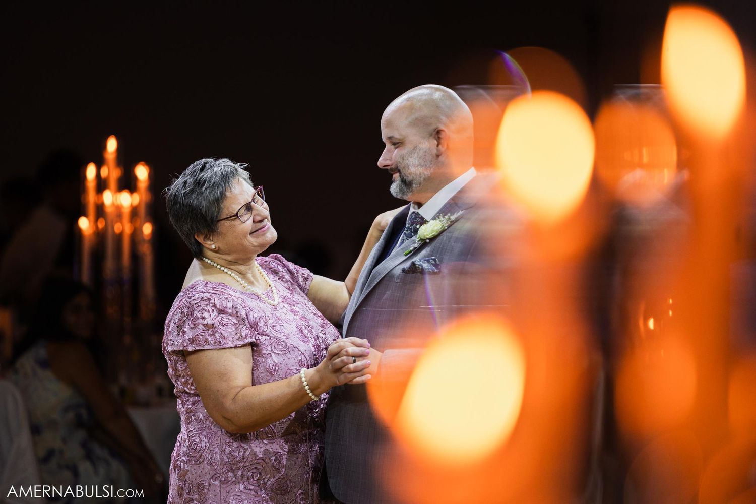 Intimate dance moment captured with bokeh lighting effect and candles in background.