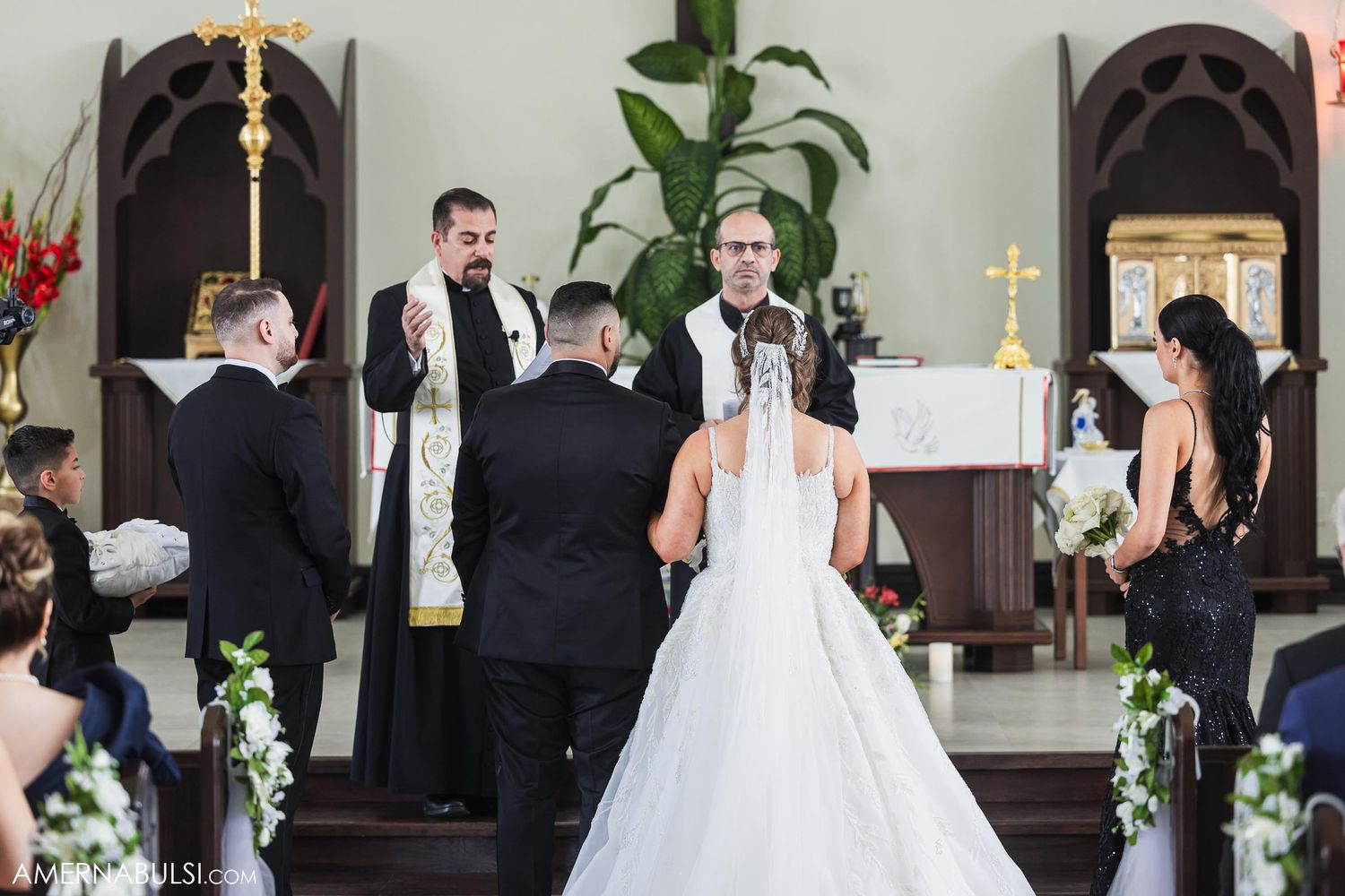 Traditional church wedding ceremony with clergy and decorative floral arrangements at the altar.