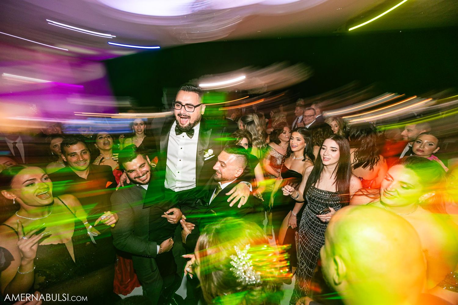 Energetic wedding party scene with dynamic lighting and crowd on dance floor.