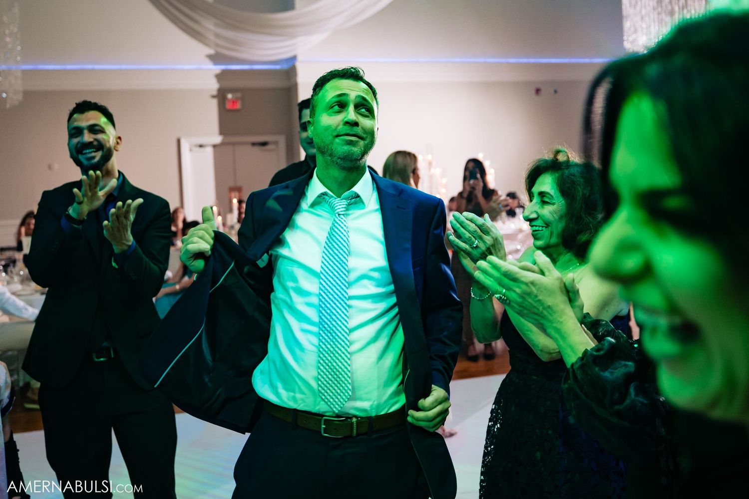 Reception party scene with green lighting and celebrating guests on dance floor.