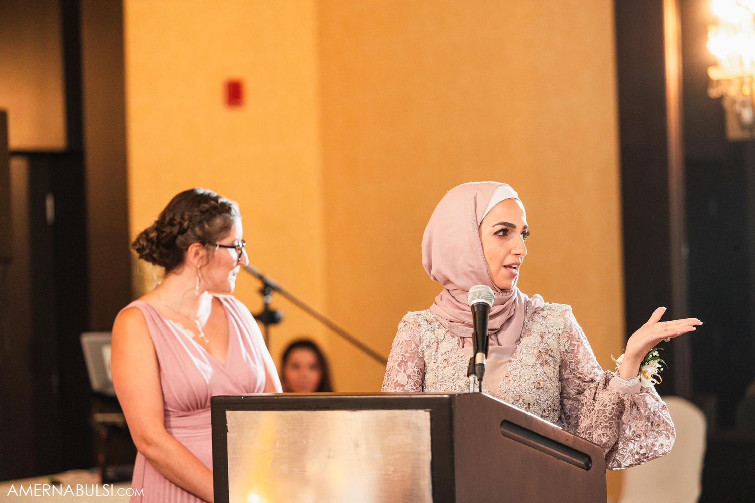 Two guests giving speeches at an elegant wedding reception with decorative lighting.