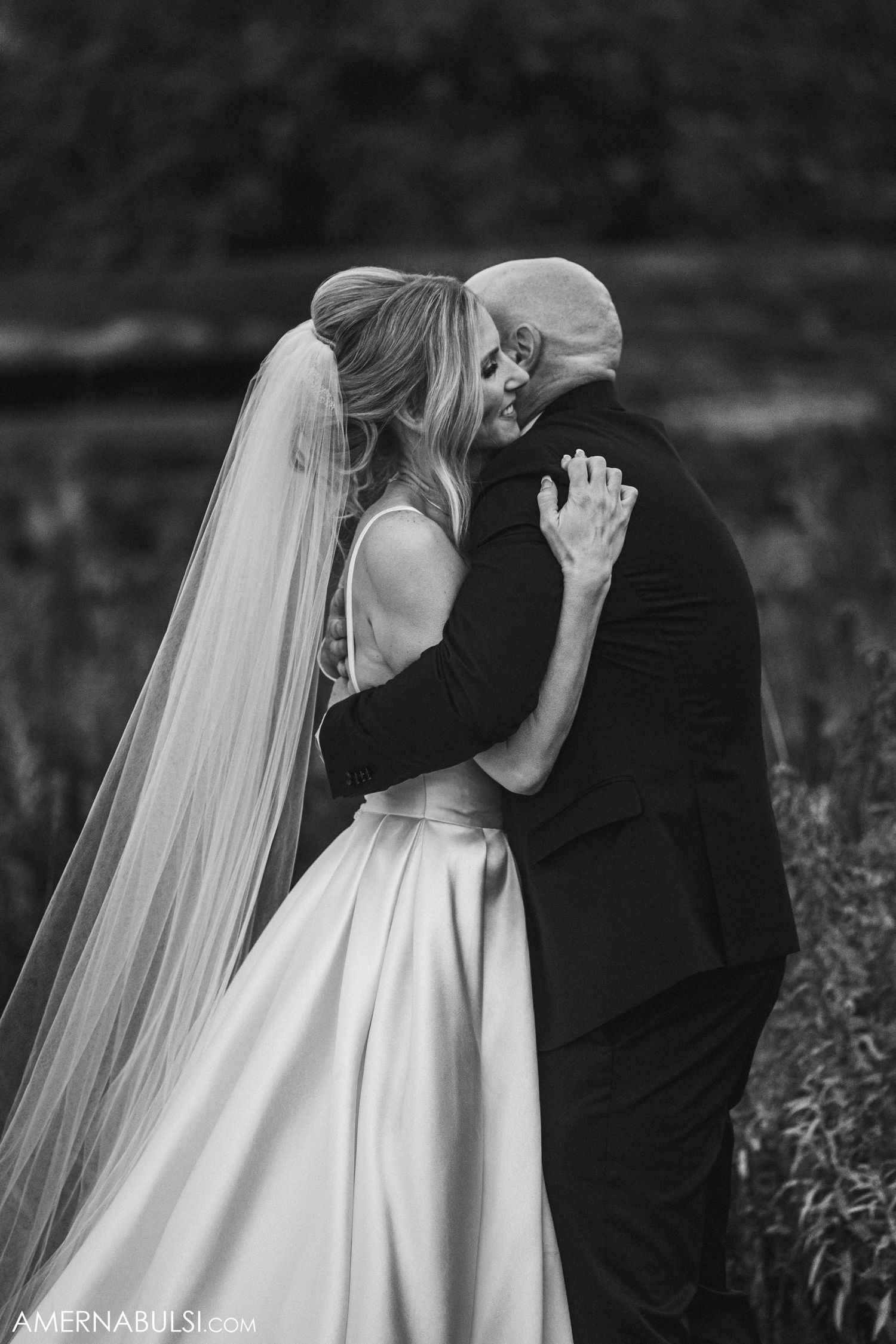 Black and white portrait of a bride and groom sharing an intimate moment in a field.