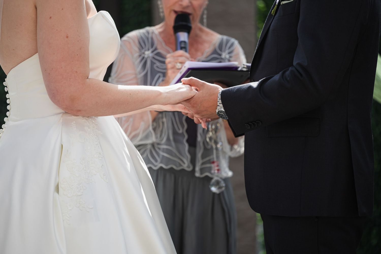 Couple holding hands at wedding altar with officiant.
