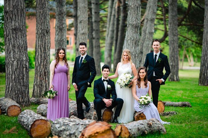 Wedding party poses among tall pine trees in a natural forest setting.