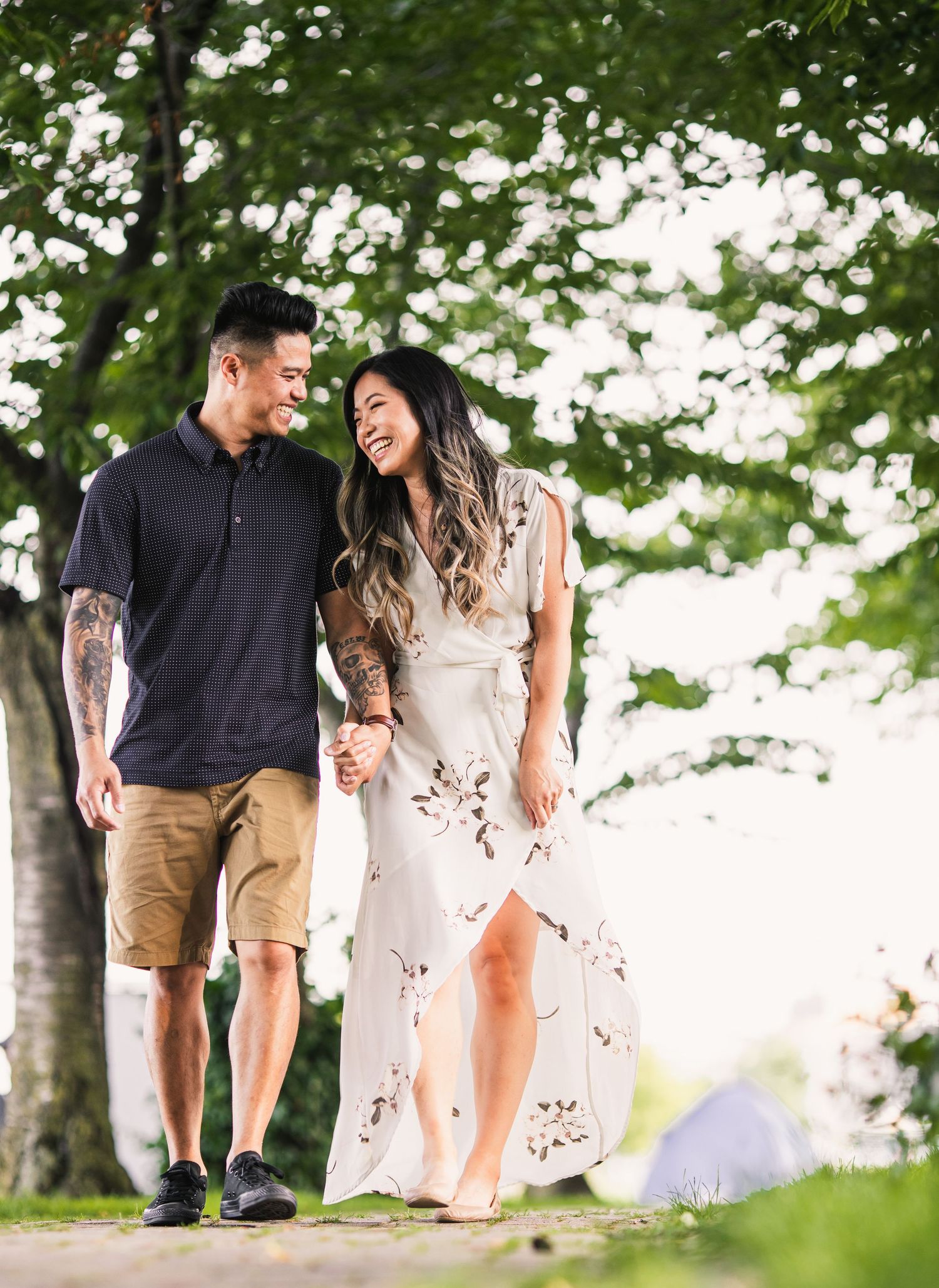 Couple walking through lush green park setting on sunny summer day.
