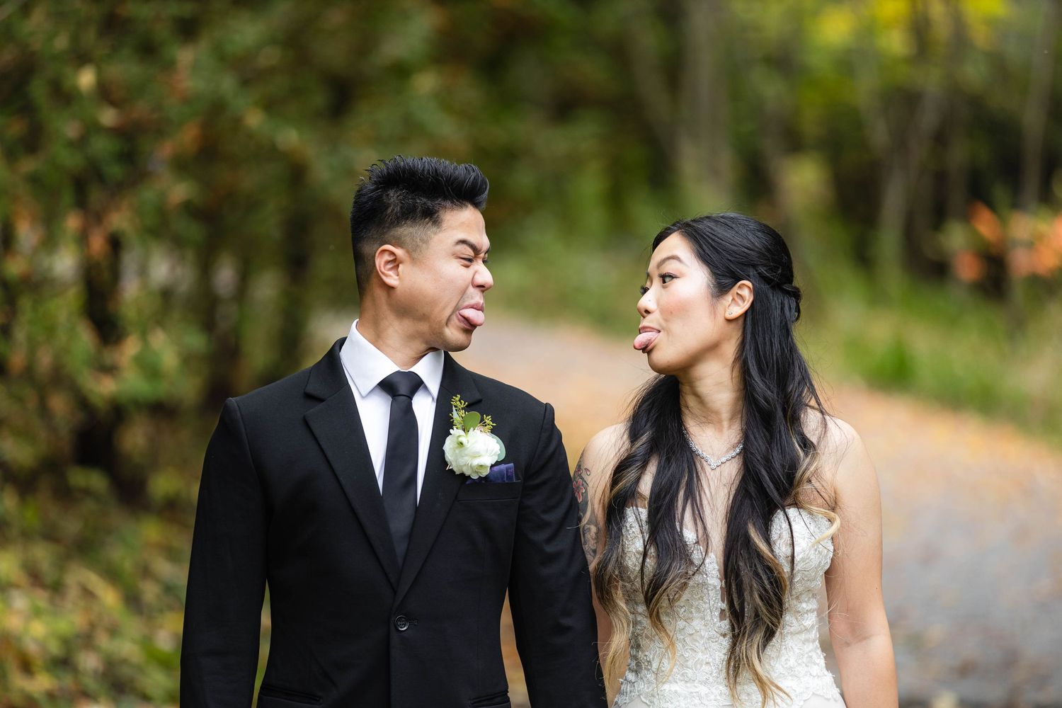 Candid moments of a wedding couple walking through an autumn forest path.