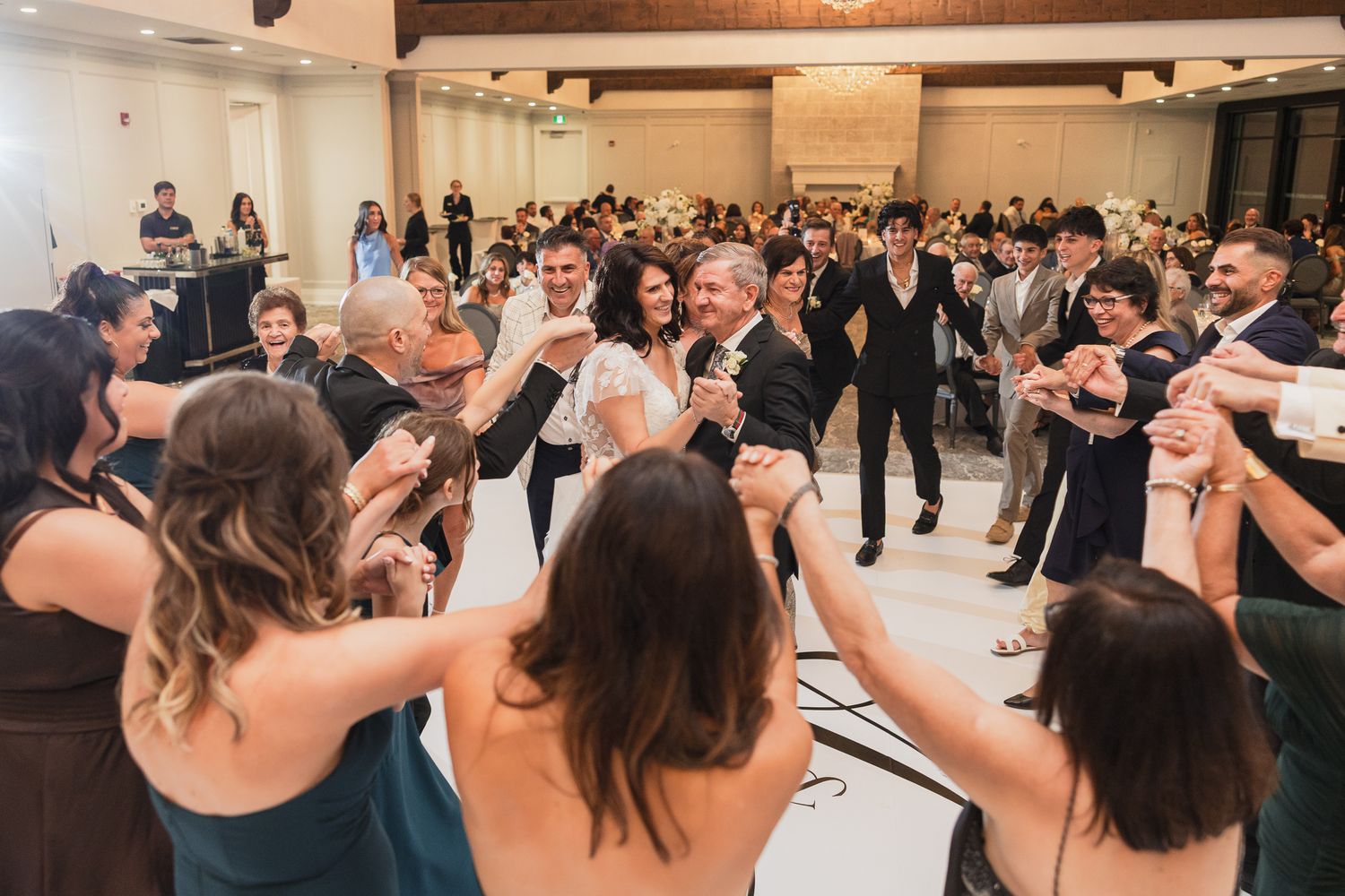 Joyful wedding reception dance with guests forming a circle around the happy couple on the dance floor.