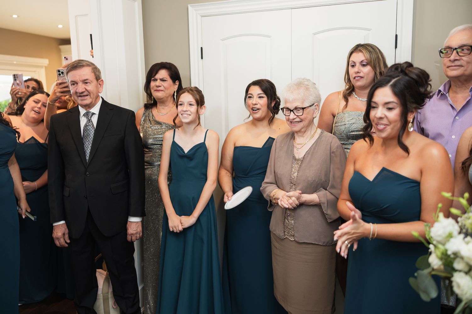 Wedding party group photo with bridesmaids in teal dresses indoors.