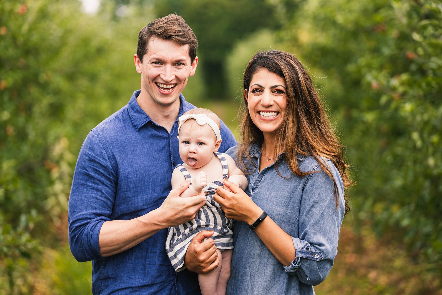 Family portrait session captured in a lush green outdoor setting during golden hour.
