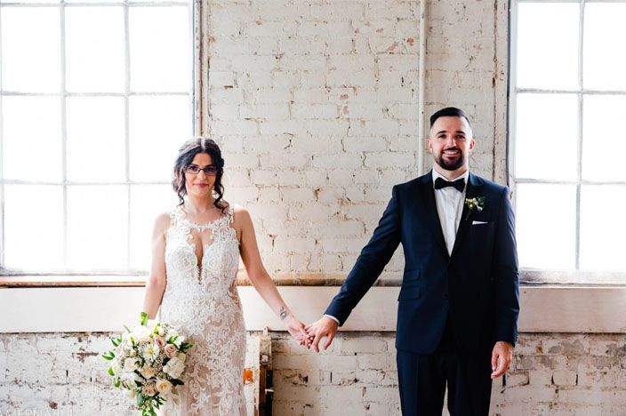 Candid wedding moments captured in an industrial brick loft space with natural window light.