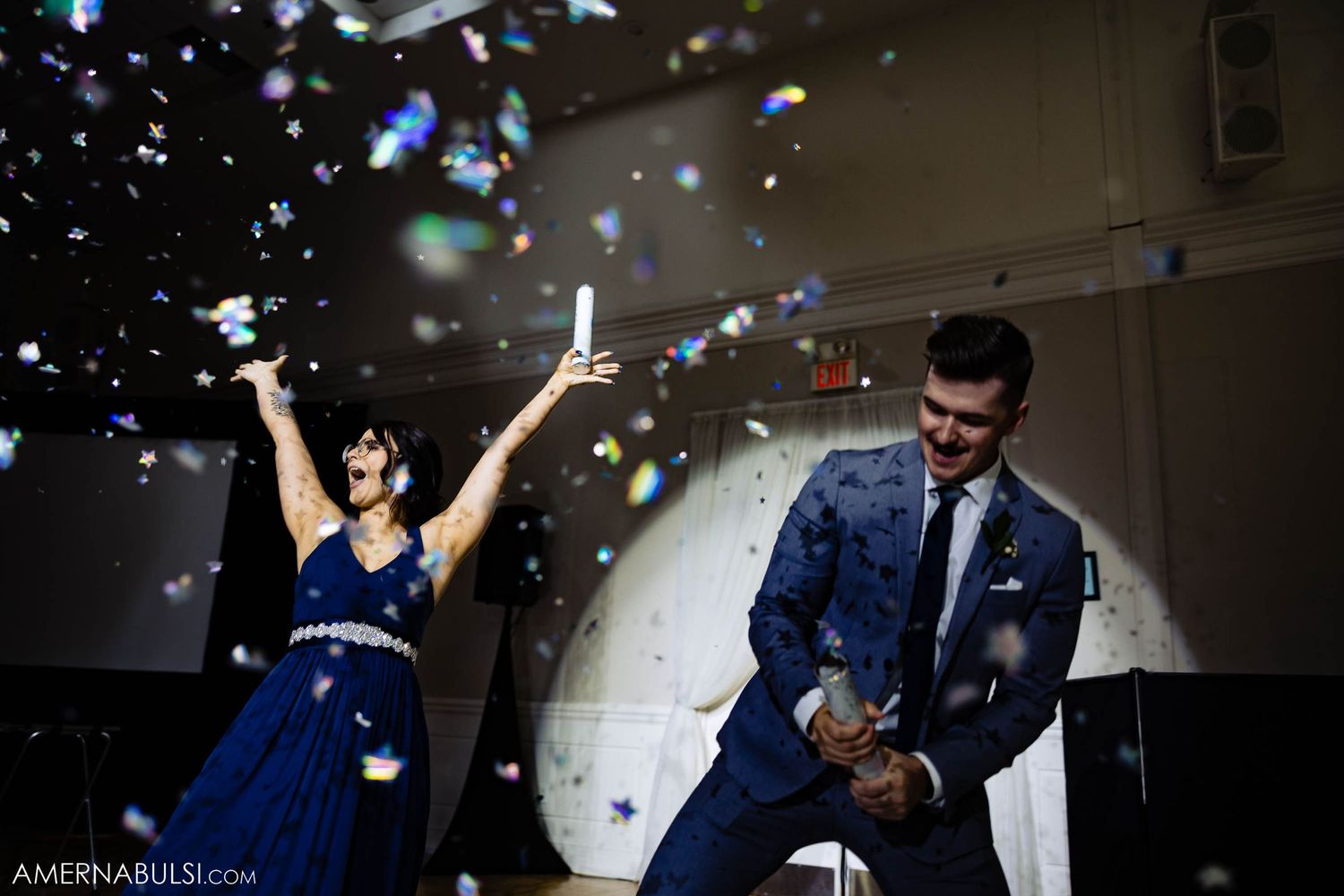 Wedding celebration with confetti falling as attendants dance under reception venue lighting.