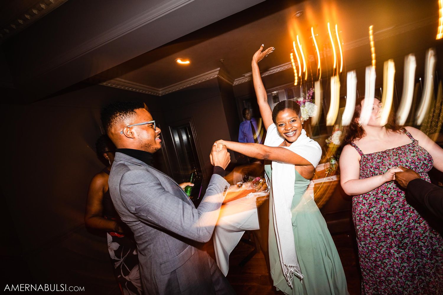 Reception party dancers celebrating near illuminated menorah display.