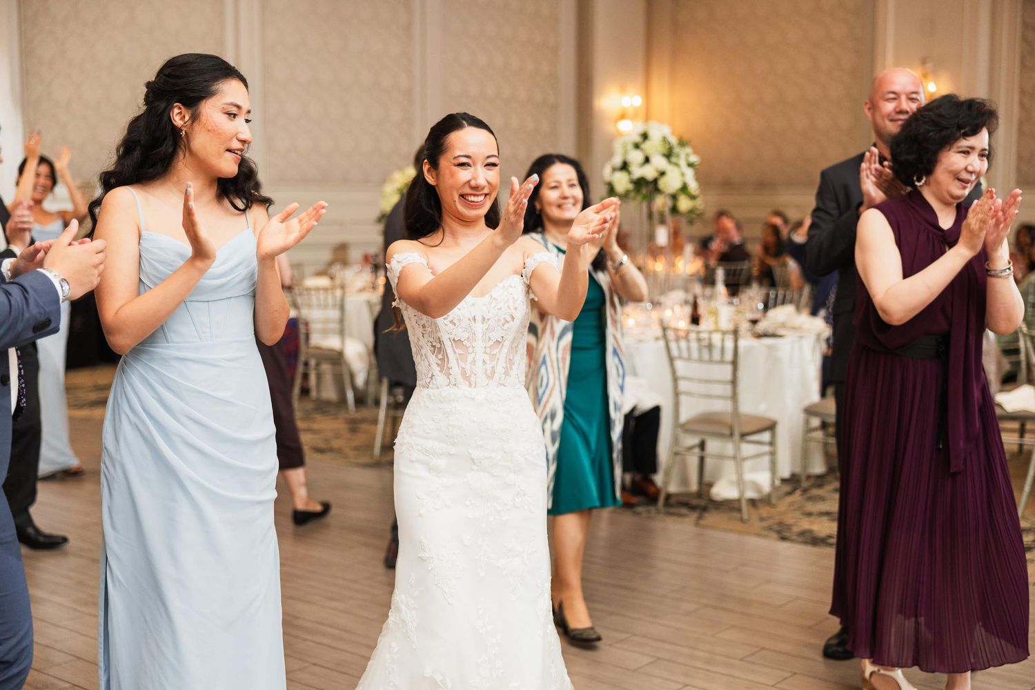 Wedding celebration with guests dancing and laughing on the dance floor in formal attire.