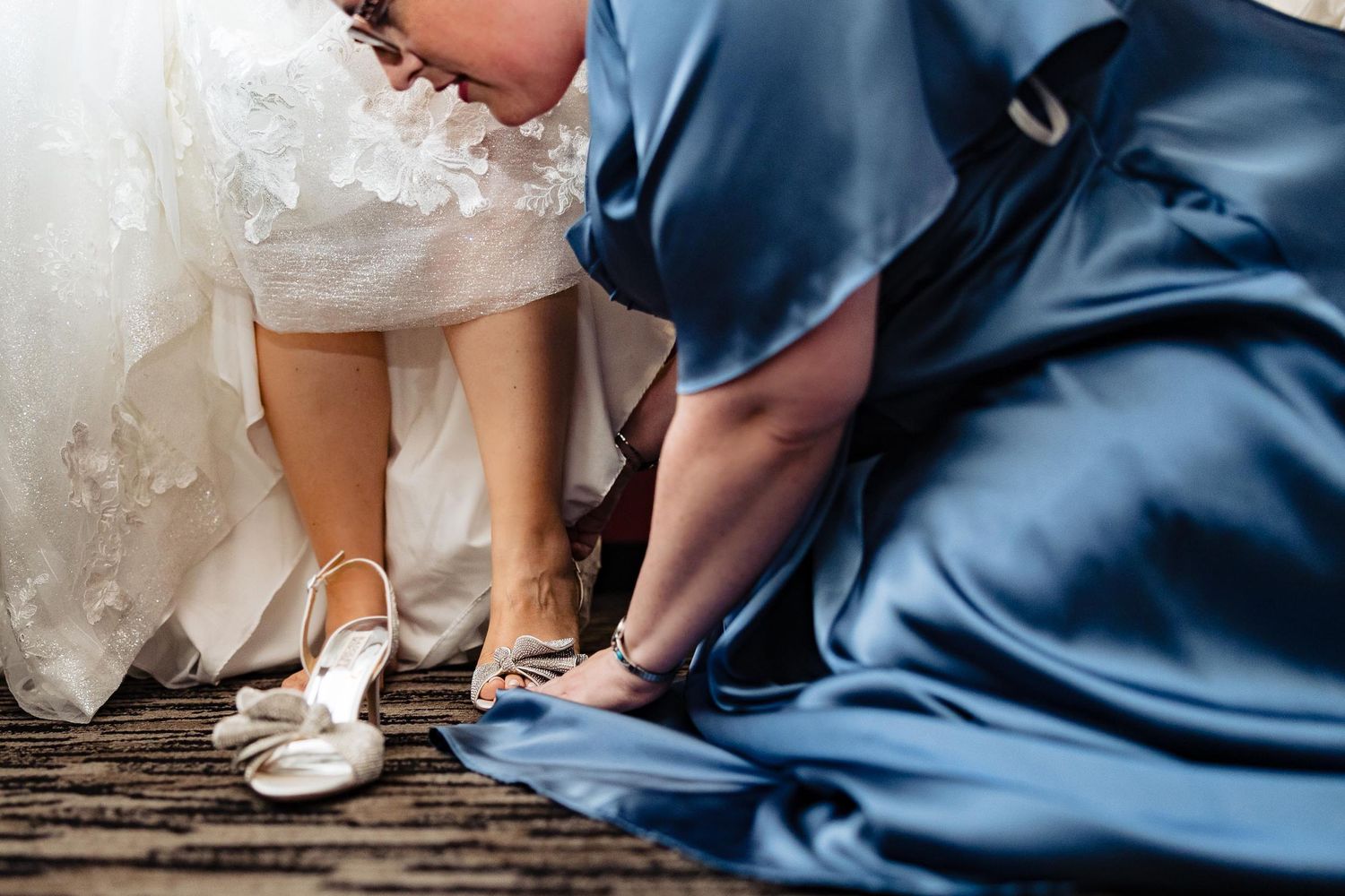 Close-up shot of white bridal shoes being adjusted against blue fabric.