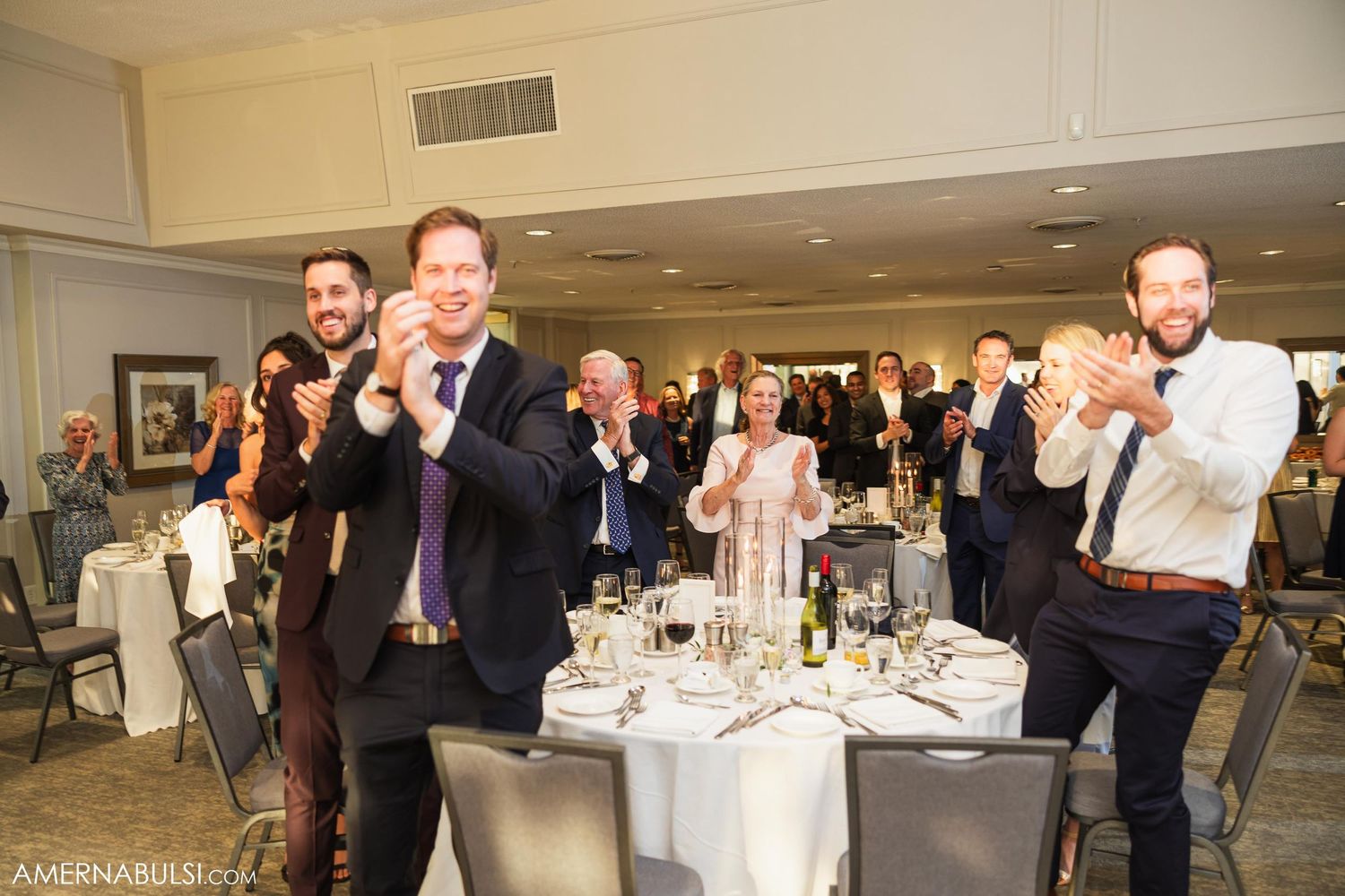 Wedding guests clap and cheer enthusiastically during the reception festivities.